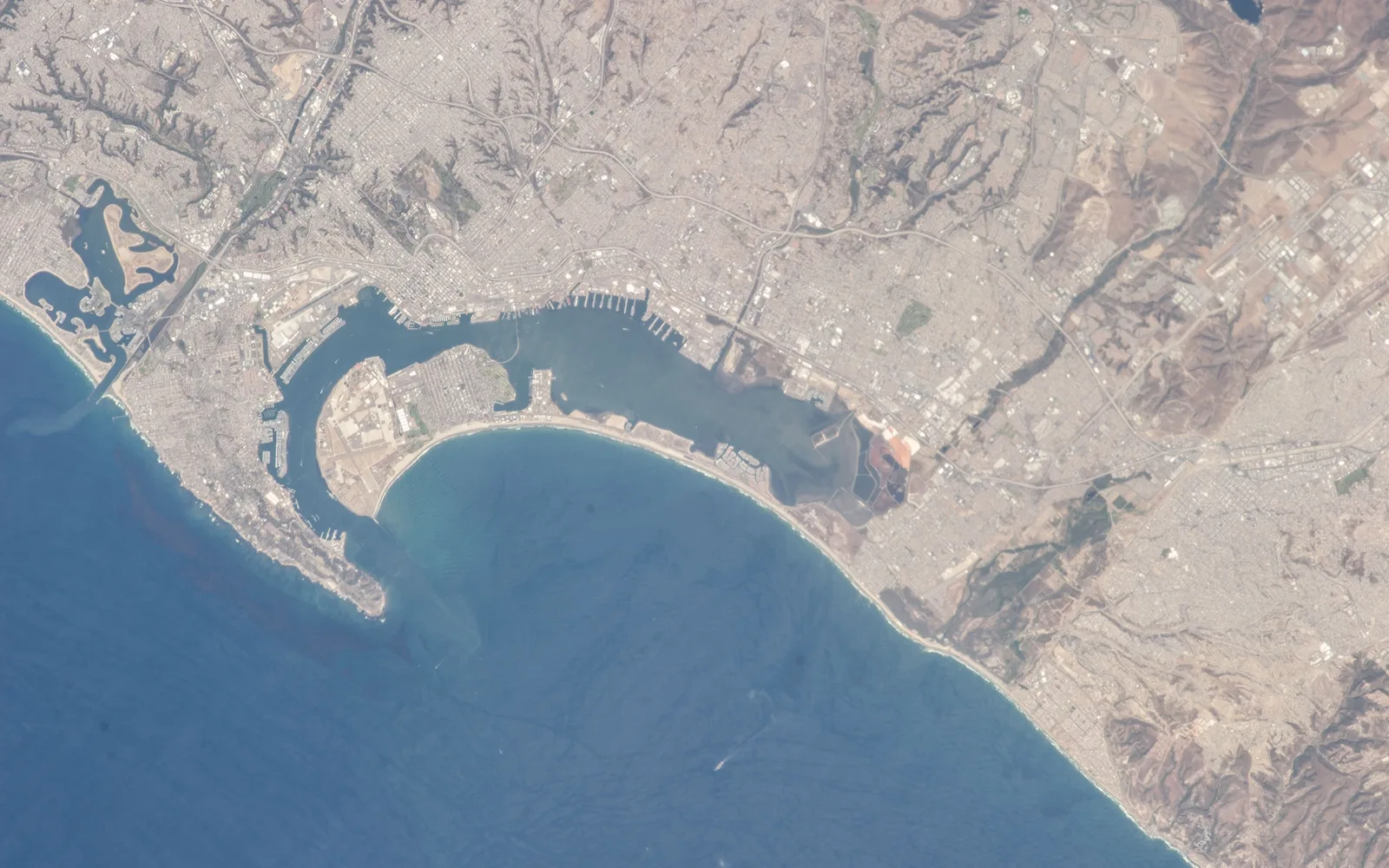 Satellite photograph from the International Space Station showing the San Diego Bay region and the Tijuana area, with the Tijuana River visible where it meets the Pacific Ocean